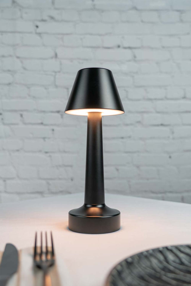 Short black cordless table lamp on restaurant table top
